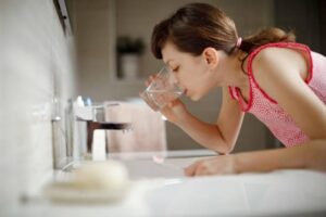 洗面台でうがいをしようと水を含む女性